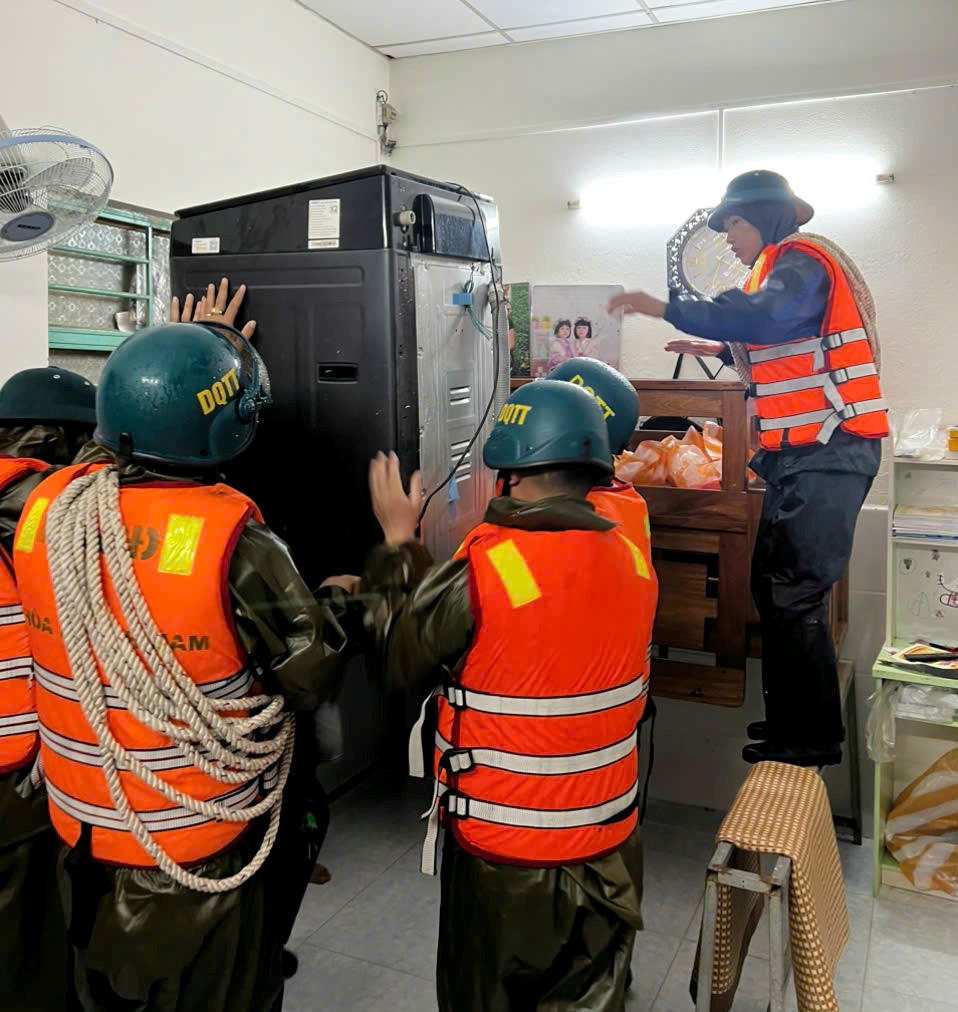 Lực lượng chức năng phường Hòa Khánh đưa đồ đạc của người dân bị ngập nước lên vị trí cao. Ảnh: CV.