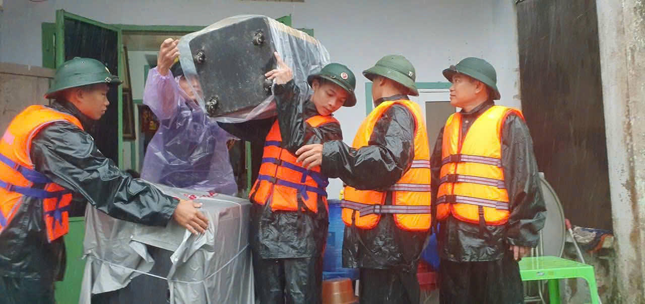 Cán bộ chiến sĩ Kho 55 hỗ trợ người dân di dời đồ đạc. Ảnh: Quang Hùng. 