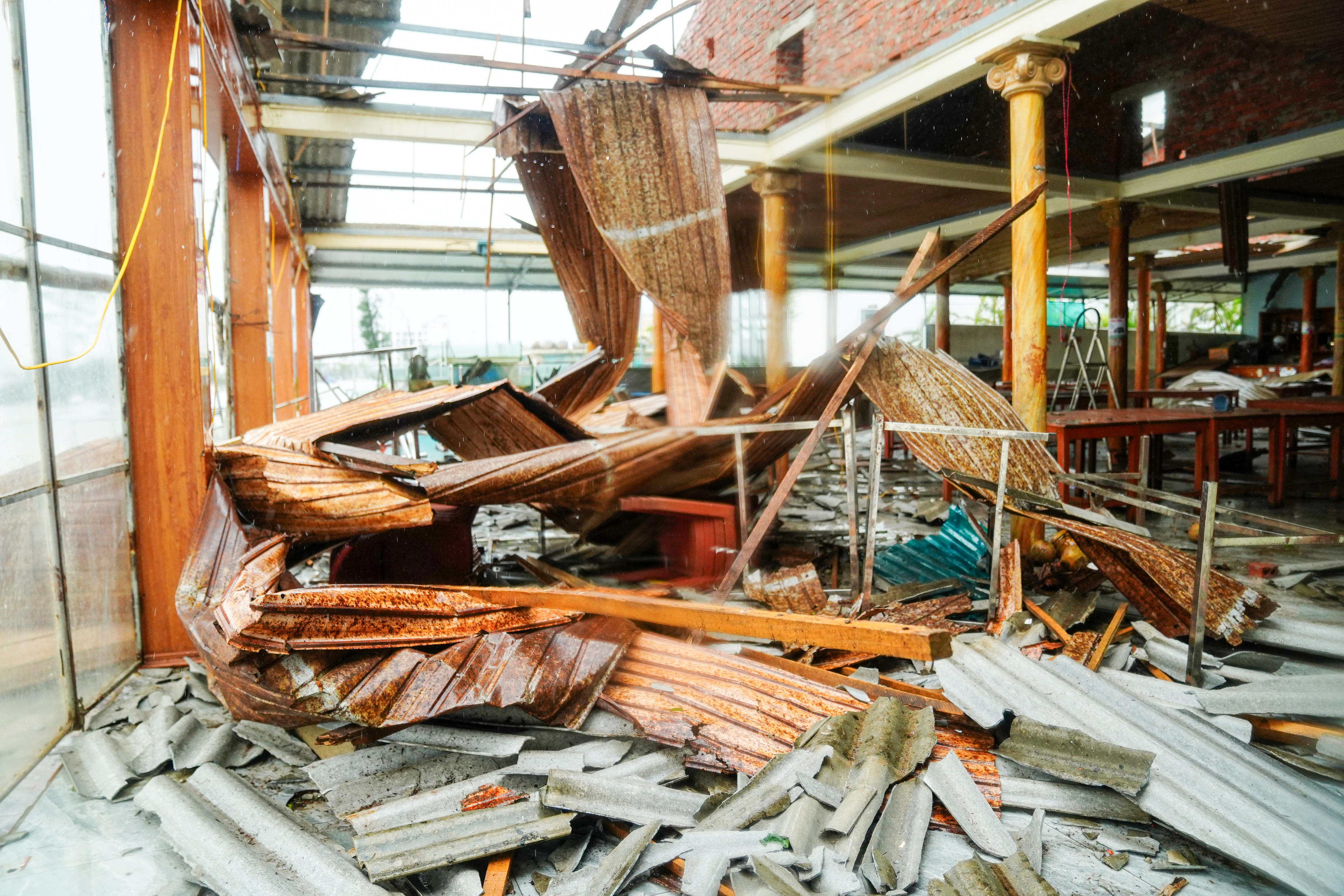 Những mảnh tôn, biển hiệu vỡ nằm la liệt giữa nền gạch ướt đẫm mưa. Ảnh: Cẩm Kỳ.