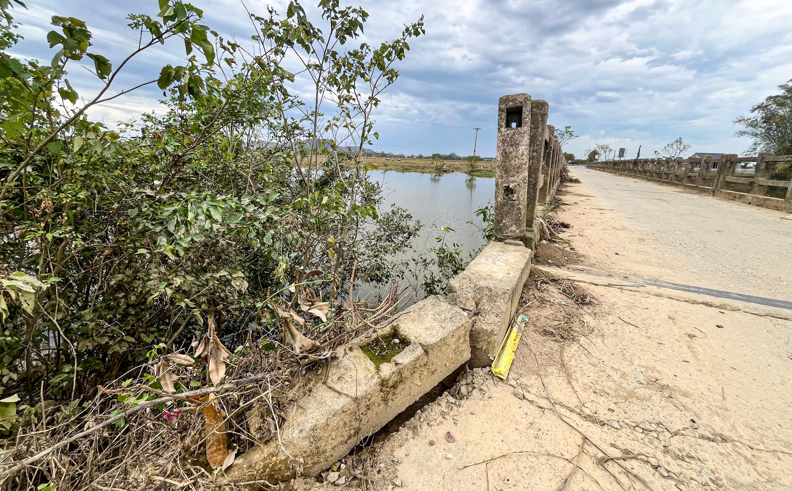 Hai bên đầu cầu, nền đường bị sụt lún, tạo thành những rãnh sâu, mỗi khi mưa xuống lại đọng nước. Ảnh: Cẩm Kỳ