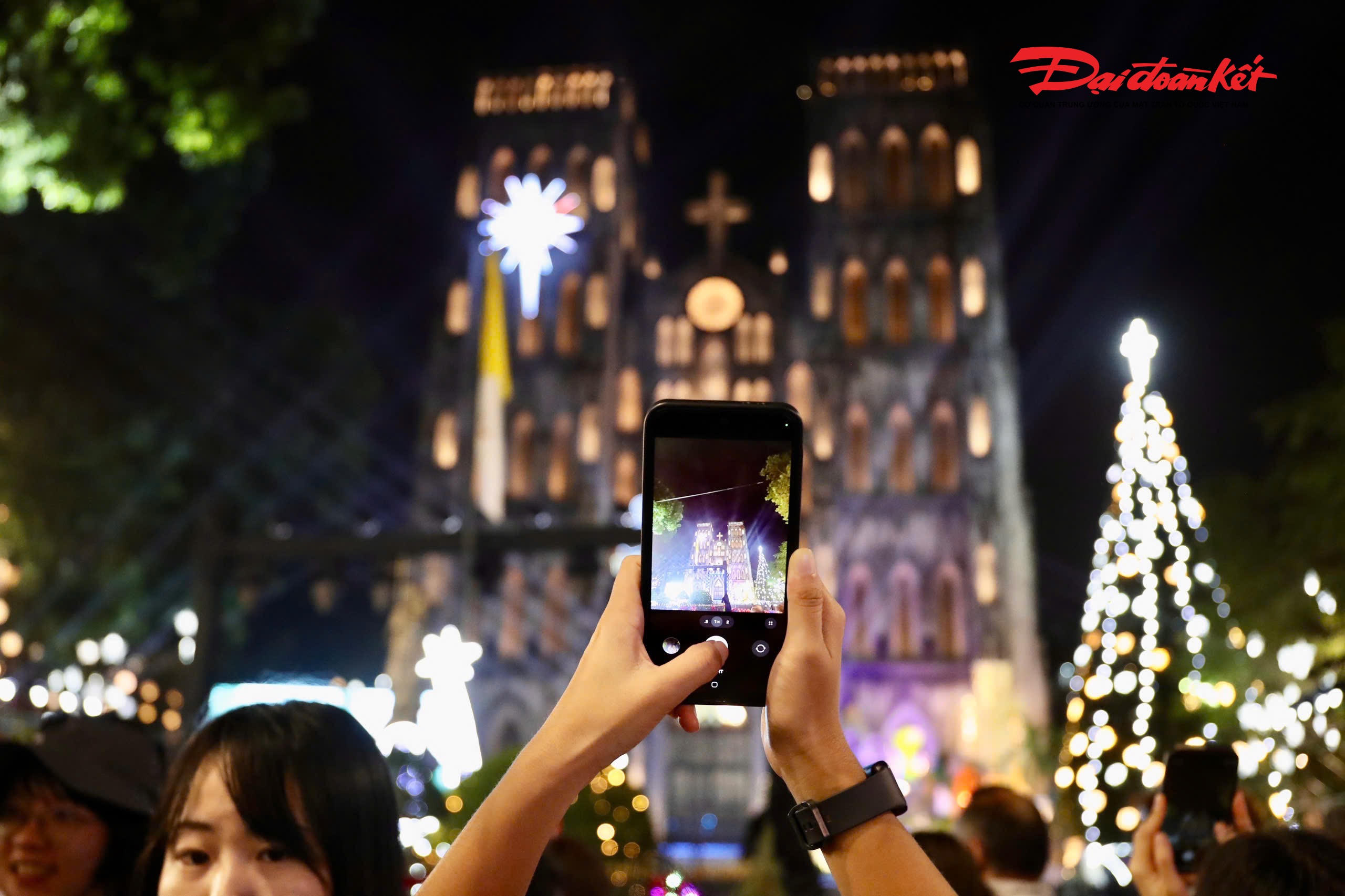 Nhiều người sử dụng điện thoại ghi lại hình ảnh Nhà Thờ lớn rực rỡ đêm Giáng sinh.