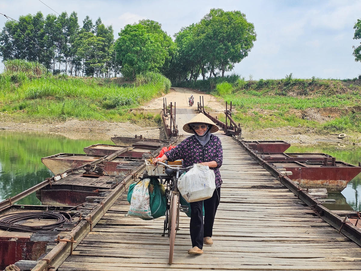Người dân đi lại trên cây cầu phao nhỏ hẹp, xuống cấp suốt gần 30 năm qua. Ảnh: Đình Minh