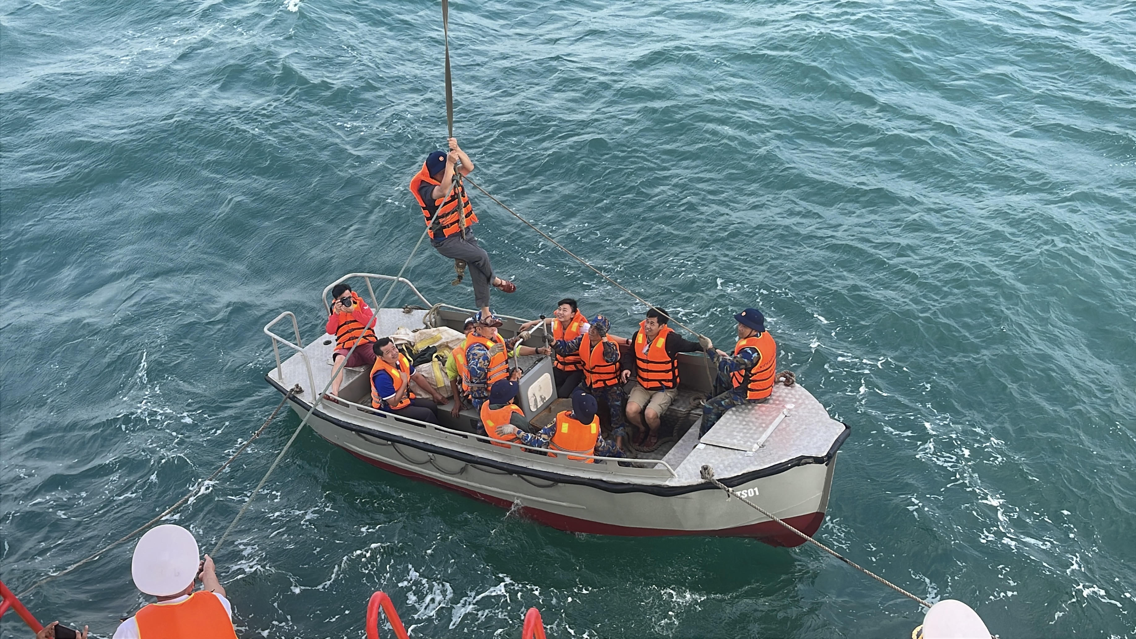 Lần lượt từng người bám vào sợi dây thừng để được kéo lên nhà giàn. Dù vất vả nhưng mọi người đều mong muốn đặt chân lên nhà giàn. Ảnh: Đoàn Xá.