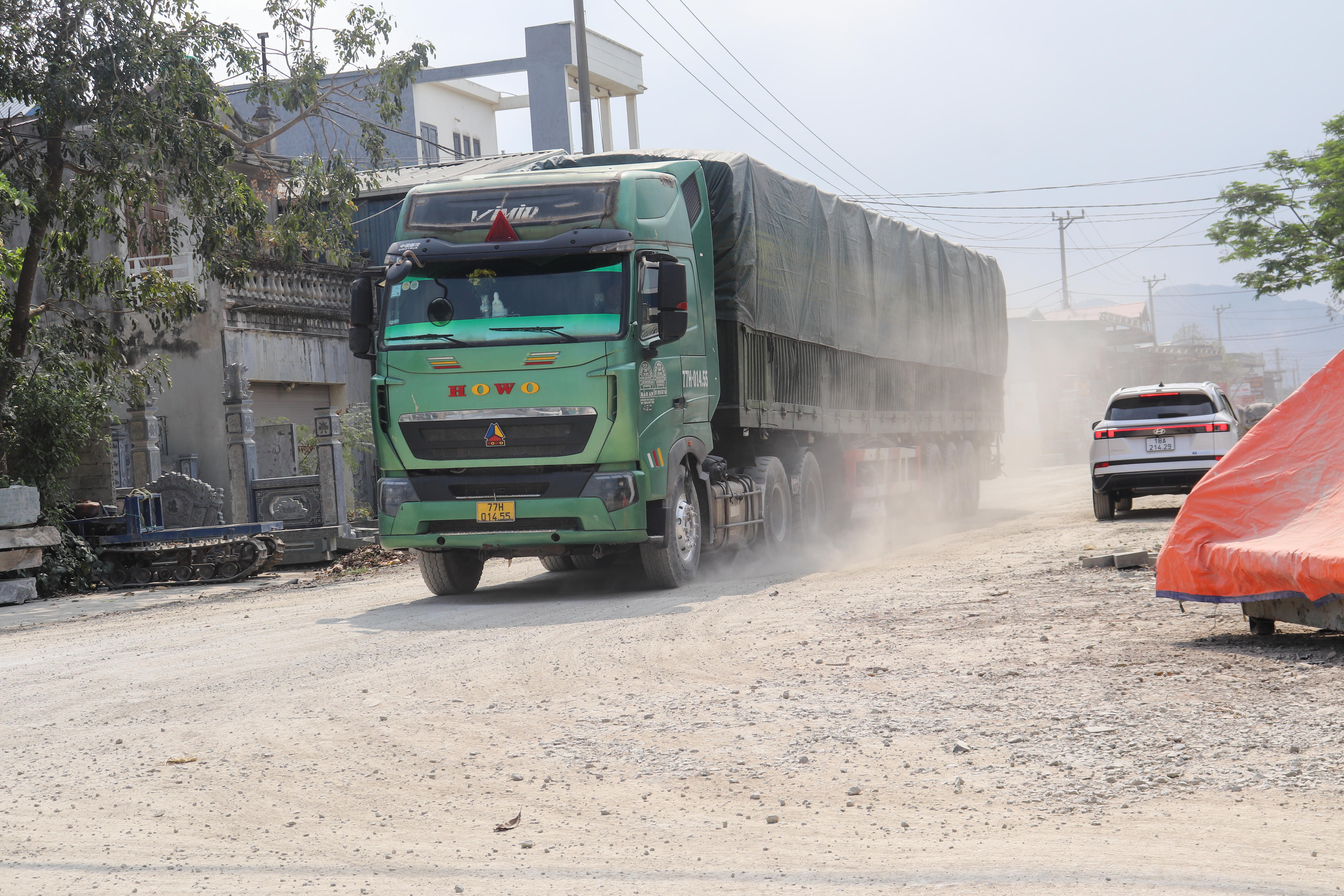 Mỗi khi xe tải lớn chạy qua, bụi lại cuốn lên trắng xóa, phủ kín các xưởng chế tác đá ven đường. Ảnh: Đình Minh